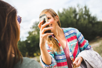 Portrait of woman photographing through smart phone