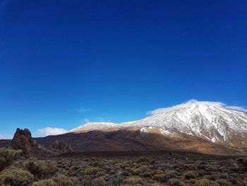 Scenic view of snowcapped mountains against clear blue sky