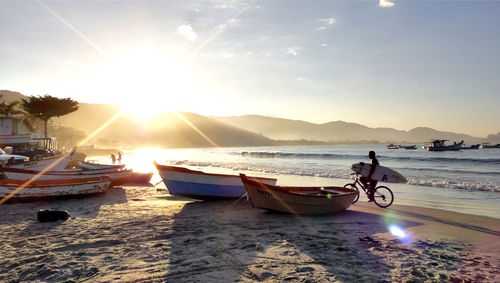 Boats moored on beach against sky during sunset