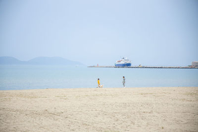 People on beach against clear sky