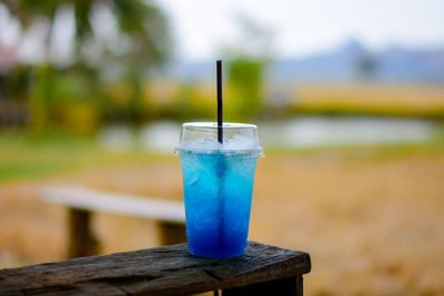 Blue soda in a plastic glass placed on a wooden table