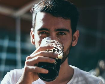 Close-up portrait of a young man drinking glass