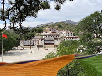 Built structure by trees and buildings against sky