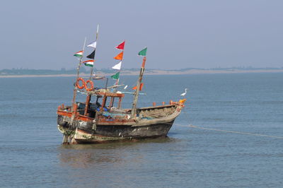 Fishing boat in sea against clear sky