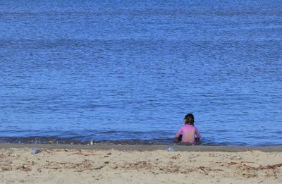 Rear view of woman sitting on beach