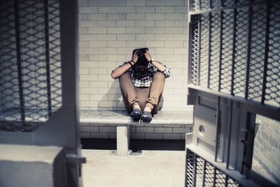 Full length of man sitting on seat at prison