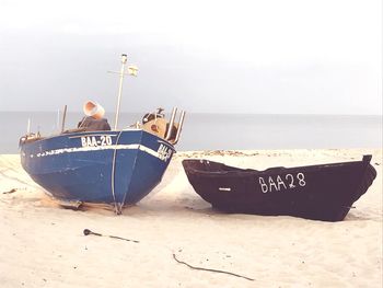 Boat moored on beach against sky