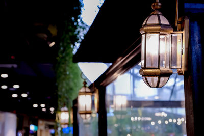 Low angle view of illuminated lamp hanging on building