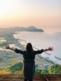 Rear view of woman standing by sea against sky