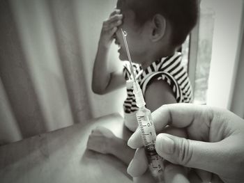 Cropped hand of doctor holding syringe by boy