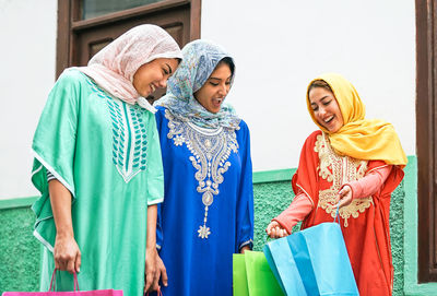 Woman wearing hijab while showing her shopping bag to friends in town