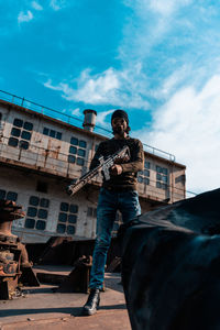 Low angle view of man standing on guitar against sky