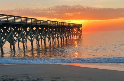 Pier over sea against sky during sunset