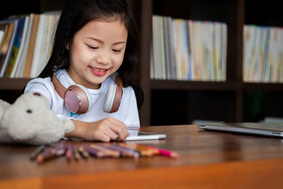 Close-up of girl using digital tablet while sitting at desk