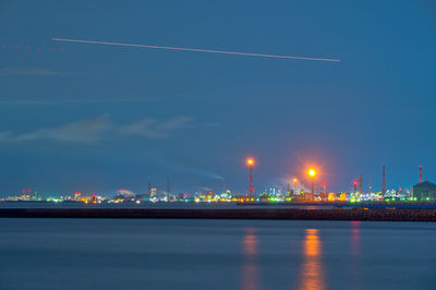 Illuminated bridge over river against sky at night