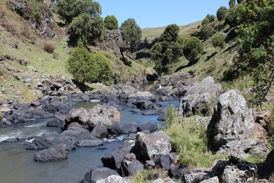 Scenic view of stream amidst rocks against sky