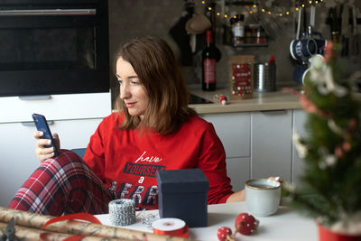 Midsection of woman holding coffee while sitting at table