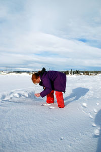 Side view of teenage girl bending on snow covered field