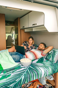 Rear view of woman sitting on bed at home