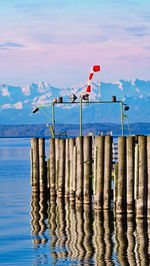Wooden posts in sea against sky