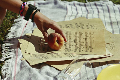 Close-up of hand holding apples on sheet music at park