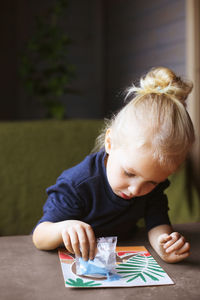 Little blonde kid girl creating sand picture of dinosaur. leisure activity indoors. creative hobby