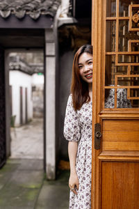 Portrait of smiling woman standing at entrance of building