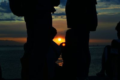 Silhouette people by sea against sky during sunset