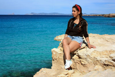 Girl in aummer at sea on the crazy cliff of formentera with crystal clear blue water in cala saona