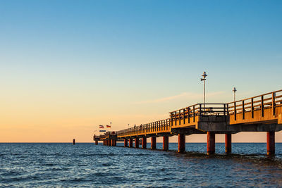 Pier over sea against clear sky during sunset