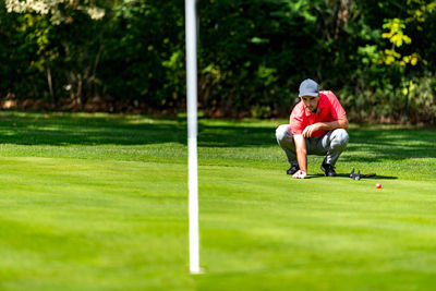 Young golfer playing golf on a beautiful sunny day, reading green