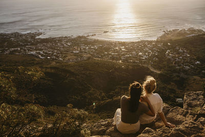 Friends admiring sea sitting on rock at signal hill