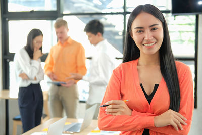 Portrait of smiling businesswoman with colleagues in background