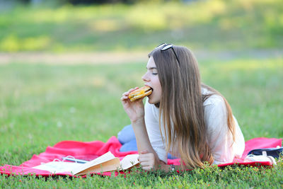 Young woman sitting on book at field