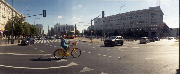 Cars on city street by buildings against sky