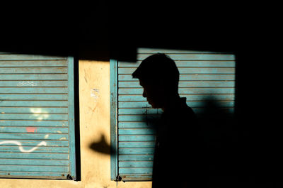 Side view of silhouette man standing against window