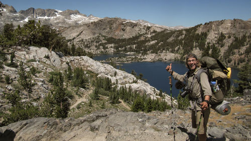 Portrait of smiling hiker standing against river and mountains