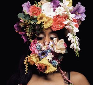 Midsection of woman with bouquet against black background