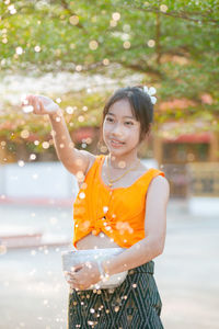 Portrait of young woman standing against waterfall