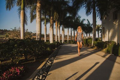 Woman standing on footpath amidst trees