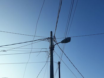 Low angle view of electricity pylon against blue sky