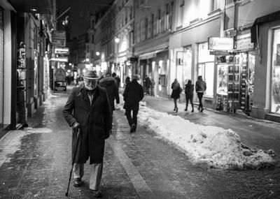 People walking on illuminated street at night