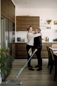 Side view of romantic lesbian couple embracing each other while doing housework at home
