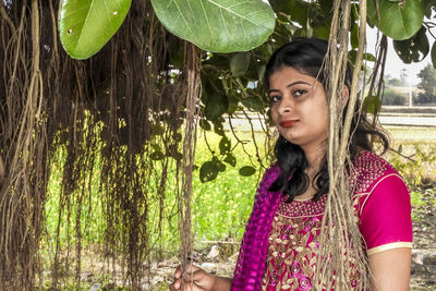 Portrait of woman against tree trunk