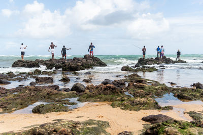 Fishermen on the rocks catching fish with their fishing poles on the beach of rio vermelho.