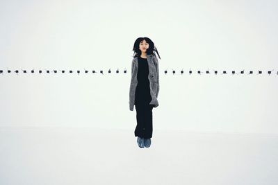 Full length portrait of woman standing against white background