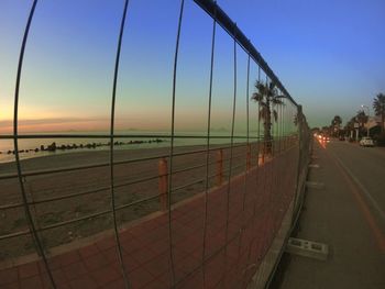 Road by sea against clear sky during sunset