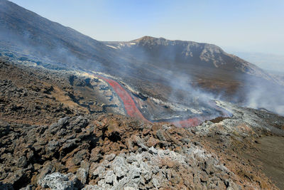 Glowing lava flow flowing on etna volcano in sicily , with smoke and lava flow channel 7 june 2022
