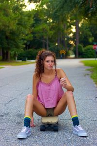 Portrait of girl smoking cigarette while sitting on skateboard