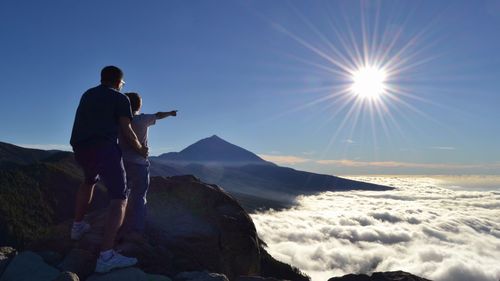 Sun shining through clouds over mountain